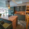 Moderne Inselkueche Mineralgruen mit Holzarbeitsplatte